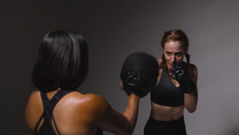 Studioaufnahme-Von-Zwei-Reifen-Frauen-In-Fitnesskleidung,-Die-Gemeinsam-Boxen-Und-Sparring-Trainieren